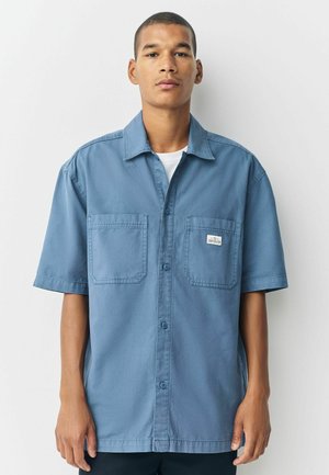 Blue short-sleeved button-up shirt with two chest pockets, made of a smooth fabric, featuring a collar and subtle label detail.