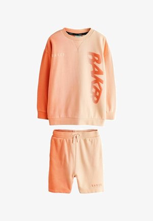 Znojeno roza pulover in ujemajoče se kratke hlače z vrvico, na puloverju spredaj napis "BAKER" in na robu hlač.