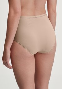 High-waisted naakt ondergoed van gladde stof, met platte naden en zonder zichtbare hardware, wat zorgt voor een naadloze uitstraling.