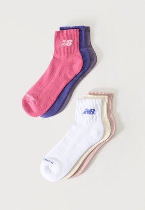 Seš potītes zeķes rozā, violetā, pelēkā, baltā, krēmkrāsā un bēšā krāsā, katrai ir ribota aproce un New Balance logotips uz potītes.