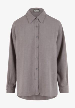 Gray long-sleeve button-up shirt made of soft fabric. Features a pointed collar, front buttons, and a slightly curved hem.
