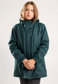 Dark green waterproof jacket with a high collar, elastic cuffs, snap buttons, and a relaxed fit. Features side pockets and smooth texture.