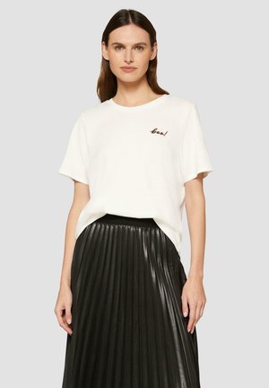T-shirt en coton blanc à manches courtes, avec un texte brodé marron "cool!" associé à une jupe plissée en cuir noire.