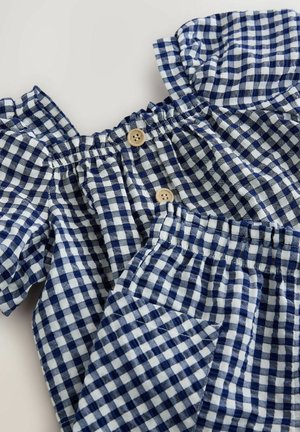 Blauw en wit geruite stofset, met ruches aan de mouwen, een elastische halslijn, houten knopen en een elastische tailleband.