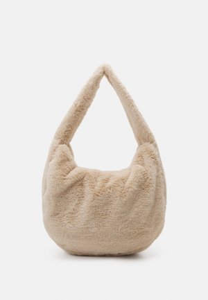 Beżowa miękka torebka na ramię z futerkiem ekologicznych, z krótkim, grubym paskiem i zaokrąglonym dnem, prezentowana na jednolitym białym tle.