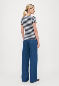Striped t-shirt in navy and white, fitted, paired with wide-leg blue denim jeans, featuring a classic five-pocket design and slight distressing.