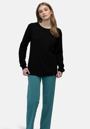 Maglietta nera a maniche lunghe con scollo rotondo abbinata a pantaloni a coste turchesi; presenta una vestibilità rilassata e una morbida texture del tessuto.