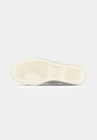 White shoe sole with textured rubber grip pattern and embossed branding. Smooth edges and curves create a streamlined profile.