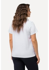 Camiseta blanca de algodón de manga corta con un corte relajado y un bajo redondeado, mostrando una textura suave y un diseño simple sin patrones.