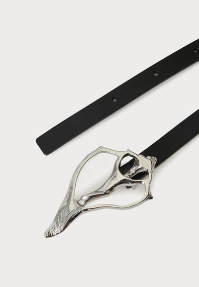 Ceinture en cuir noir avec une grande boucle décorative argentée présentant une forme organique ouverte et abstraite.