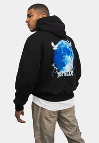 Sudadera con capucha negra que presenta un gráfico de luna azul con relámpagos y palomas, diseñada con un corte relajado y puños de canalé.