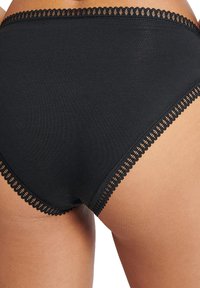 Mutande da donna in cotone nero con rifiniture in pizzo in vita e lungo le gambe, caratterizzate da una texture liscia e un design classico a slip.