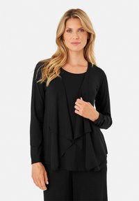 Maglietta nera a maniche lunghe con design a strati, dotata di un davanti drappeggiato e scollatura rotonda. Tessuto morbido con una vestibilità comoda.