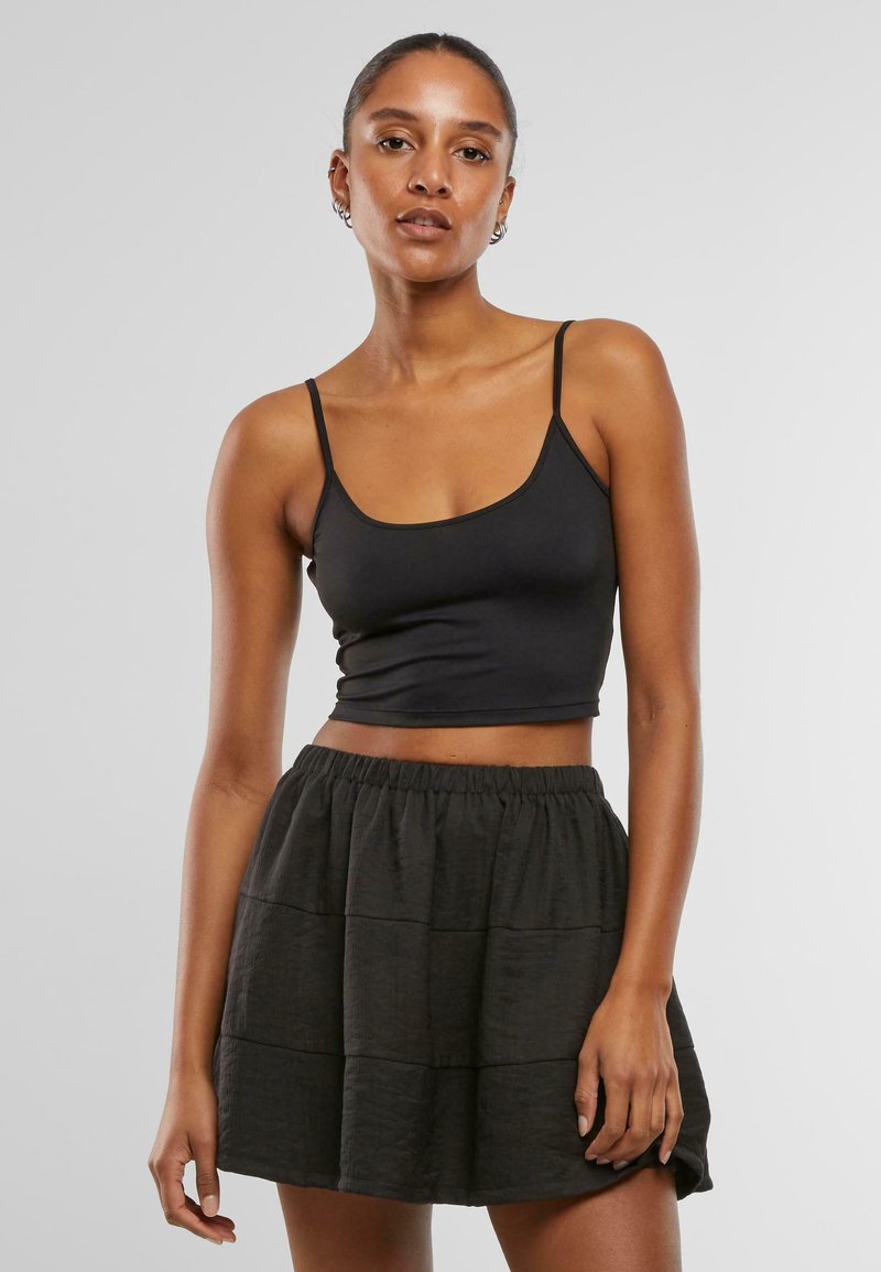 Zwarte cropped tanktop met dunne bandjes, gecombineerd met een zwarte gelaagde, gestructureerde minirok. Eenvoudig ontwerp met een elastische tailleband op de rok.