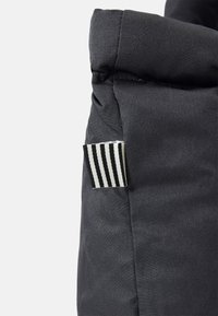 Donkergrijze stoffen tas met een gestructureerd oppervlak en een gevouwen bovenkant. Bevat een klein zwart-wit gestreept label aan de zijkant.