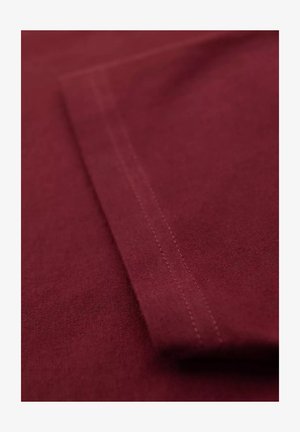 Bordowy materiał o gładkiej fakturze, z widocznym przeszyciem wzdłuż krawędzi i płaskim, złożonym wzorem.