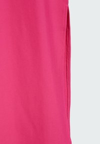 Gros plan sur un tissu rose vif avec une fente latérale montrant une couture détaillée et une texture côtelée.