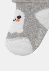 Calzino alla caviglia grigio con punta bianca. Presenta un design di pinguino in nero, bianco e arancione. Realizzato in morbido tessuto testurizzato.