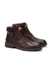 Botas de tobillo de cuero marrón con un acabado suave, diseño con cordones, detalle de hebilla lateral y costuras en contraste sutil en la suela.