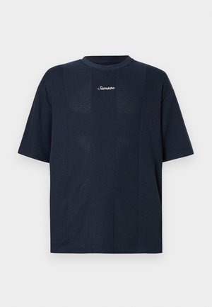 Μπλε-ναυτικό πουκάμισο σε μεγάλο μέγεθος κατασκευασμένο από υφασμάτινη υφή, με κοντά μανίκια και στρογγυλή λαιμόκοψη. Το όνομα της μάρκας "Samsoe" είναι τυπωμένο σε άσπρο χρώμα.