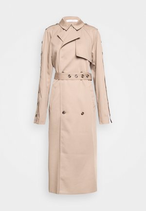 Trench coat bege com colarinho, aba frontal assimétrica, botões duplos e fechos de pressão nas mangas. Apresenta bolsos frontais.