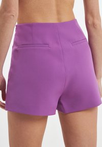 Shorts violets avec une texture lisse, taille haute et deux poches arrière. Le design est ajusté et fitted, avec des lignes épurées.