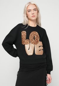 Μαύρο φούτερ με υπερμεγέθες "ΑΓΑΠΗ" σε χρυσό γκλίτερ και μεταλλική εμφάνιση. Διαθέτει μακριά μανίκια και ριμπ μέση.