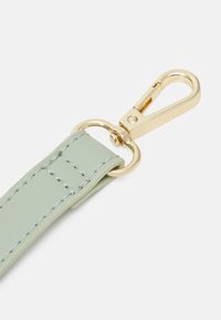 Mintgrön rem med slät yta, försedd med guldfärgad metallklämma och ring, samt kontrasterande sömnadsdetalj.