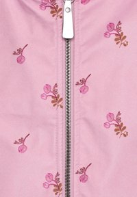 Giacca in tessuto rosa chiaro con ricami floreali in tonalità di rosa e marrone, con una cerniera argentata sul davanti.