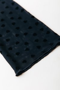 Tumši zils auduma šalle ar maziem melniem sirds rakstiem, mīksta tekstūra un apstrādātas malas. Viegls un plūstošs dizains, piemērots slāņošanai.