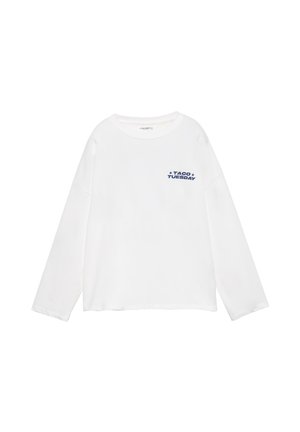 Biela košeľa s dlhým rukávom, okrúhlym výstrihom a modrým nápisom "TACO TUESDAY" s hviezdičkami na ľavej strane hrudníka.