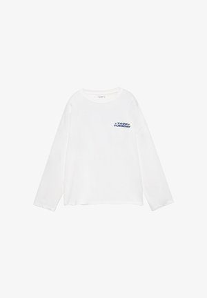 Chemise blanche à manches longues avec col rond et texte bleu "TACO TUESDAY" accompagné d'étoiles sur le côté gauche de la poitrine.