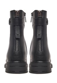 Botas de cuero negro hasta el tobillo con cremalleras traseras, correas con hebilla y suelas gruesas de plataforma vistas desde atrás.