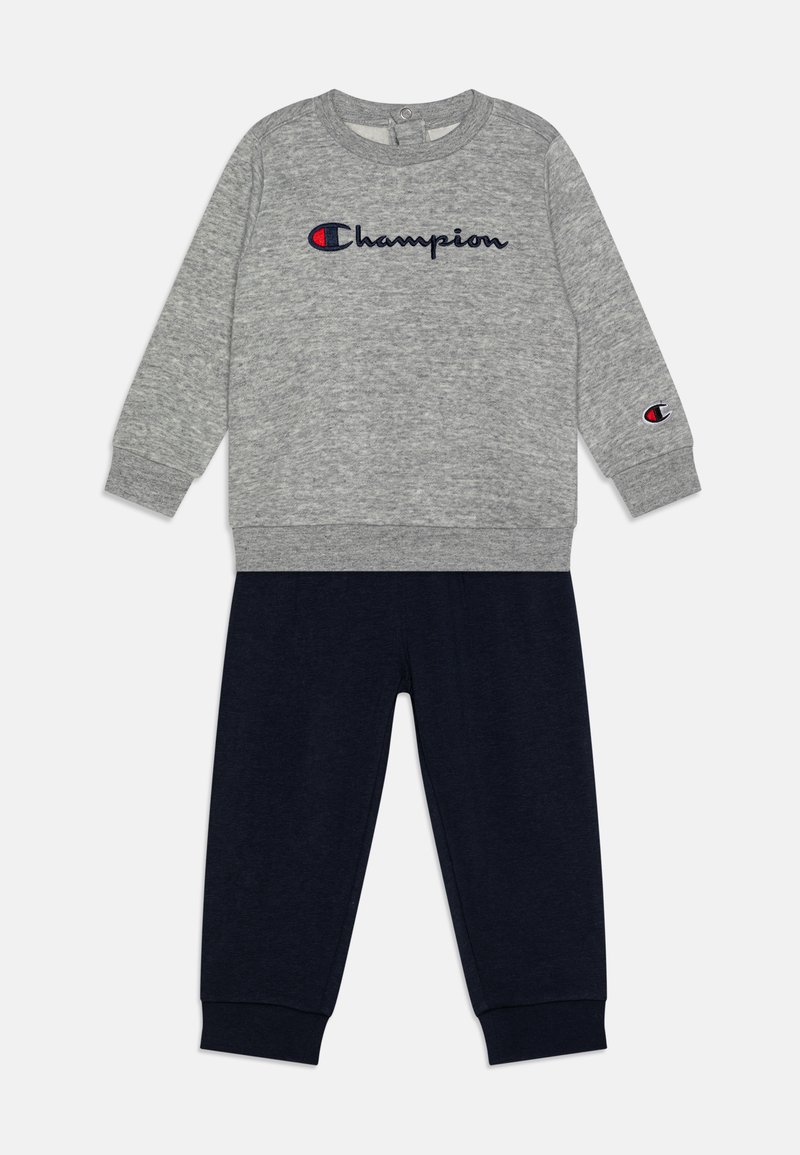 Sudadera gris con logo en azul marino, cuenta con mangas largas y puños de canalé. Acompañada de pantalones azul marino hechos de tela suave, con cintura elástica.