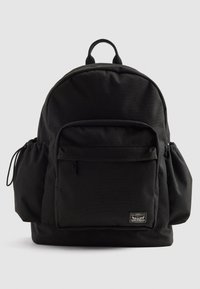 Svart ryggsekk med frontlomme med glidelås, sidelommer med snøring, bærehåndtak på toppen, og Levi Strauss & Co.-merke på den nedre fronten.