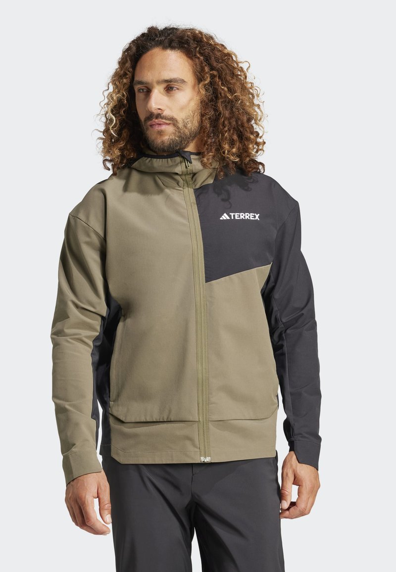 Olijfgroene en zwarte zip-up jas met capuchon, voorzien van een TERREX-logo, een soepele textuur en een contrasterend paneelontwerp.