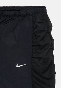 Čierne šortky Nike s elastickým pásom, s textúrovanou tkaninou na jednej strane a sieťovanou vložkou pre priedušnosť, ozdobené bielym logom.