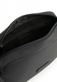 Borsa in tessuto nero con chiusura a zip, tasca interna con zip, superficie testurizzata e forma rettangolare. Etichetta visibile all'interno.