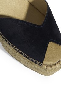 Espadrille en daim marine avec un design à bande croisée, semelle en jute naturel et détails cousus, dotée d'une doublure intérieure beige douce.