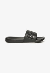 Sort slide sandal med en bred rem, der har præget tekst. Glat syntetisk materiale, flad sål og minimalistisk design.