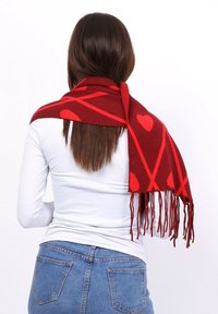 �Écharpe rouge avec un motif de cœurs rouges et de lignes diagonales, dotée d'extrémités à franges, fabriquée en tissu tissé doux.