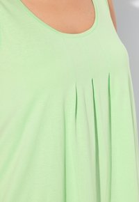 Top senza maniche verde chiaro con scollatura a barchetta, caratterizzato da pieghe verticali sul davanti, realizzato in tessuto morbido e leggero.