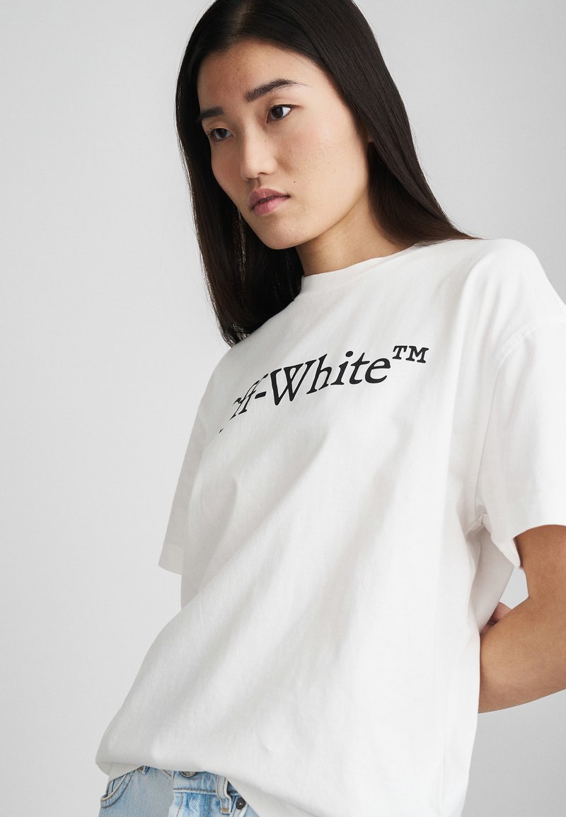 Valge puuvillane T-särk lühikeste varrukatega, mille esipinnal on must „Off-White™“ logo. Lihtne, sirge lõikega disain.