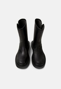 Black leather boots with a smooth texture, round toe, side elastic panels, and chunky rubber sole featuring ribbed detailing.