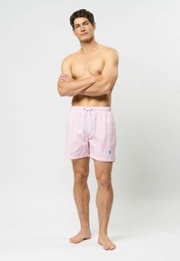 Rosa gingham badetights med elastisk midje og snøring, med en liten blå logo. Lett materiale og knelang design.