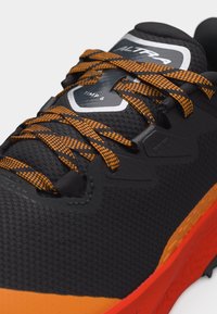 Μαύρο και πορτοκαλί παπούτσι για τρέξιμο σε μονοπάτια με κορδόνια με σχέδιο, υφασμένο επάνω μέρος και πορτοκαλί σόλα με την ένδειξη "Altra Timp 6".