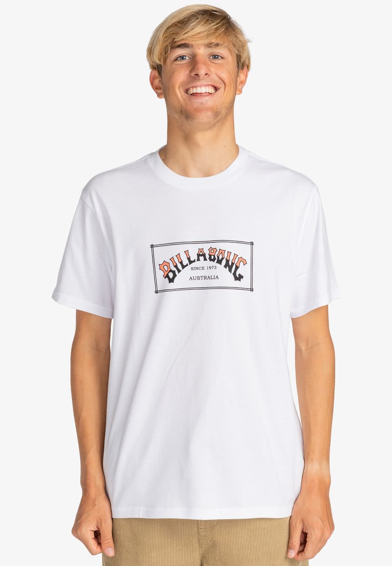 Bílá bavlněná tričko s grafickým logem v oranžové a černé barvě, s textem "Billabong od 1973 Australia" umístěným na hrudi.