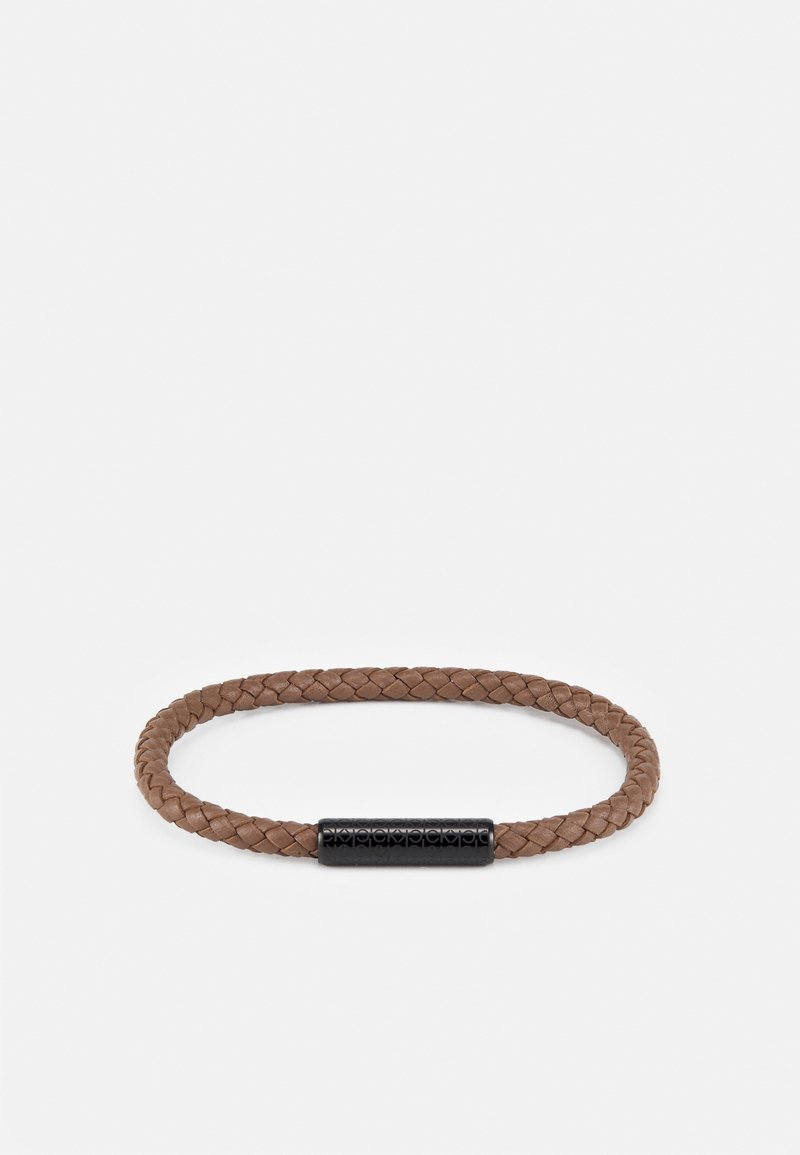 Bracelet en cuir tressé marron avec une fermeture magnétique cylindrique noire ornée de motifs gravés subtils.