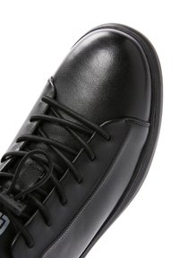 Scarpa in pelle nera con una finitura liscia, punta rotonda, sistema di allacciatura centrale e suola a profilo basso con dettagli di battistrada minimi.