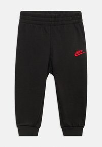 Pantaloni della tuta neri realizzati in tessuto morbido, con un logo Nike rosso sulla coscia sinistra, vita elastica e polsini aderenti.
